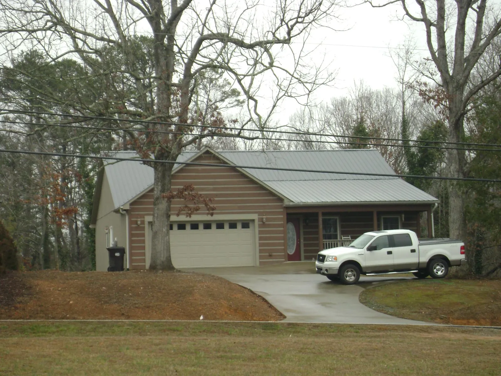 Gray metal roof on a log sided house with an attached two car garage in Oxford